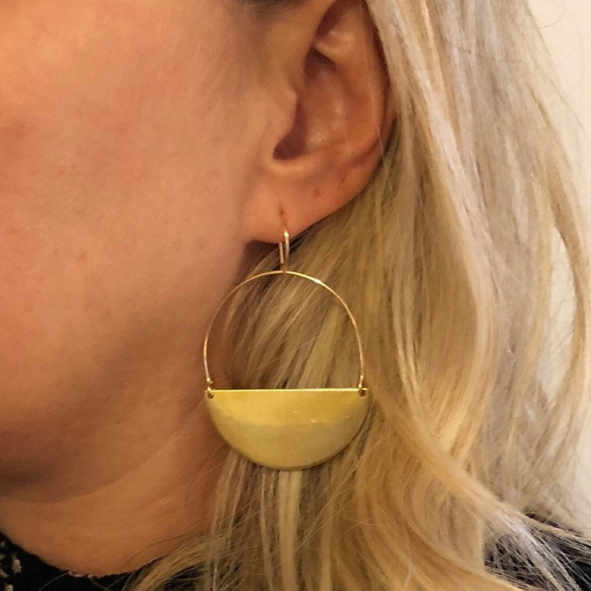 Model wearing brass half moon smooth finish earrings from laurane elisabeth