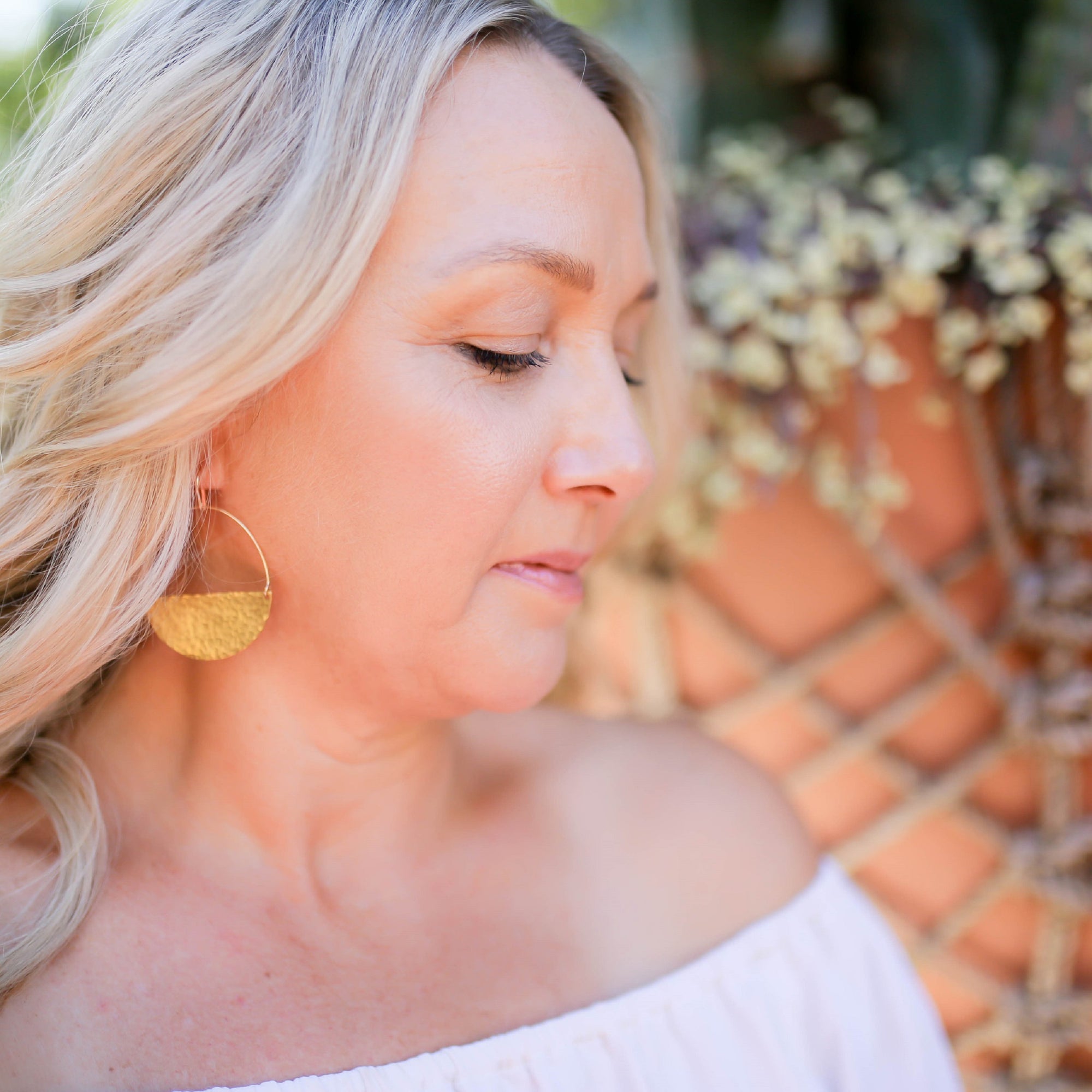 Model wearing brass half moon hammered earrings from laurane elisabeth